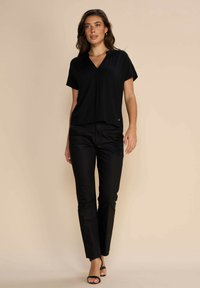 Black short-sleeve v-neck top with pleated design, paired with black straight-leg pants. Smooth fabric, minimalistic style, and subtle logo detail.