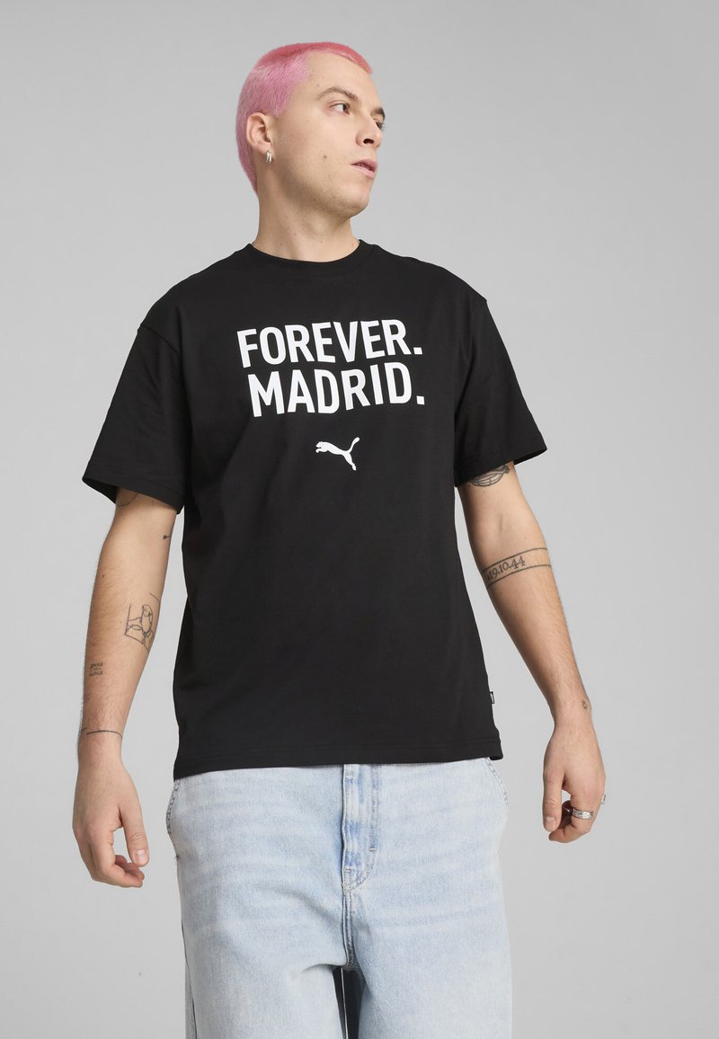 Melna kokvilnas T-krekls ar lieliem baltiem burtiem "FOREVER. MADRID." un mazu baltu Puma logotipu. Īsas piedurknes un brīvs griezums.