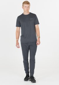 Grau Sportshirt und passende Hose, beide aus leichtem Material. Das Shirt hat einen Rundhalsausschnitt; die Hose hat schmal zulaufende Beine und seitliche Akzente.