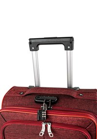 Maleta de tela roja con herrajes negros, asa telescópica de aluminio, compartimentos con cremallera y una pequeña cerradura con combinación.