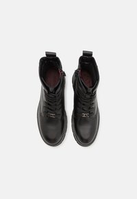 Bottines en cuir noir avec un bout rond, un design à lacets, une fermeture éclair latérale et un intérieur en tissu doux.