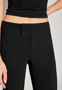 Fekete leggings magas derékpánttal és varrás nélküli kialakítással. Az anyag sima, enyhén fényes, testhezálló sziluettet biztosít.