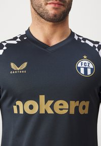 Dunkelgrau Fußballtrikot für Herren mit kurzen Ärmeln, ausgestattet mit weißen und schwarzen Karomustern, goldenen Markenzeichen und einem V-Ausschnitt.