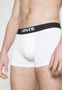 Bienti boxer šorti ar melnu jostu, uz kuras ir Levi's logo. Audums ir gluds, ar pieguļošu dizainu un bez papildus rakstiem.