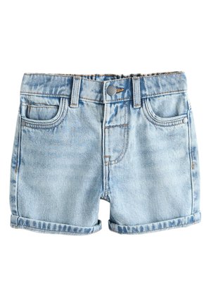 Ung dreng i en sort hat, hvid grafisk t-shirt, denimshorts, hvide sokker og sorte sneakers står og kigger opad og smiler.