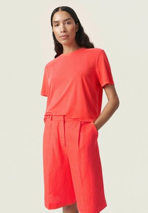 Koraalvormig T-shirt met korte mouwen en een ronde hals, gecombineerd met bijpassende knielange shorts. Gemaakt van lichtgewicht stof met een gladde textuur.
