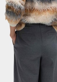 Pullover aus Wollmischung mit lockerer Struktur in Creme, Orange und Grau, kombiniert mit maßgeschneiderten Hose in Anthrazitgrau mit zwei Gesäßtaschen.