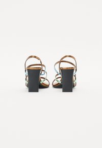 Sandales à talons bruns avec des brides bleu clair et vertes, présentant un talon carré et un design à dos ouvert. Fini en cuir lisse.