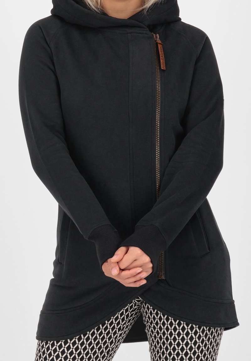 Sudadera con capucha negra, con cremallera frontal y bolsillos, que presenta un dobladillo curvado y puños acanalados. Textura suave, diseño casual.