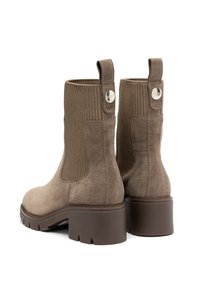 Stivali alla caviglia in suede marrone con tessuto a coste e un linguetta, dotati di un tacco spesso marrone e un accento di logo metallico circolare.