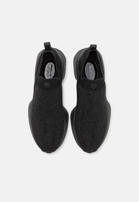 Czarne buty slip-on z teksturowaną cholewką z dzianiny i gładką gumową podeszwą. Zawierają pętelkę na zapięcie dla łatwego zakładania oraz subtelną markę.