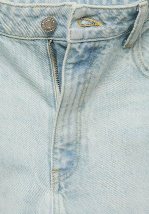 Light blue denim jeans featuring a silver zipper, metal button closure, and yellow stitching details along the waistband and zipper area.