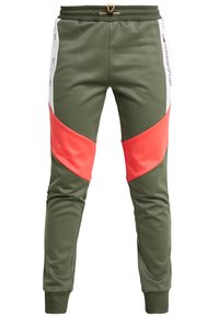 Gröna joggers med korallfärgade diagonala knäpaneler, vita sidostrimlor med grå stjärnor och Tommy Sport-logotyp på vänster sida.