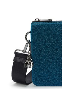 Borsa a tracolla turchese glitter con superficie testurizzata, tracolla nera regolabile e dettaglio con charm metallico. Chiusura a zip nella parte superiore.