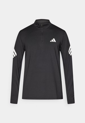 Zwart shirt met lange mouwen en een halve ritssluiting bij de hals; heeft een wit Adidas-logo op de borst en drie witte strepen op elke arm.