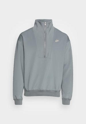 Lys grå pullover sweatshirt med høj krave, halv lynlås foran og ribbede manchetter. Har et lille logo på brystet. Glat stoftekstur.