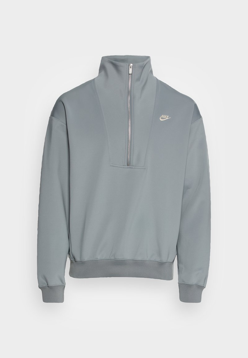 Felpa leggera grigia con colletto alto, zip parziale frontale e polsini a coste. Presenta un piccolo logo sul petto. Tessuto con texture liscia.