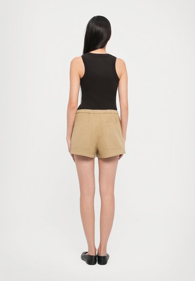 Black ribbed tank top paired with khaki shorts featuring two back pockets. The shorts have a relaxed fit and an elastic waistband.