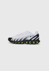 Witte sportschoenen met zwarte accenten, groene bubbelachtige demping en een strak ontwerp met een gelaagde kleurverloop en logo-details.