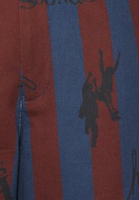 Tecido de algodão com riscas verticais em azul e marrom, com silhuetas pretas de figuras em ação; inclui detalhes de costura contrastantes.