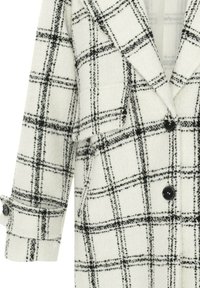 Manteau en laine blanche avec motif à carreaux noirs, col cranté, trois boutons noirs et détail au poignet sur la manche.