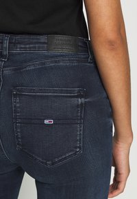 Mörka jeans av denim med en kroppsnära design, som har en bakficka och ett märkespatch i läder. Diskreta sömmar på midjebandet.