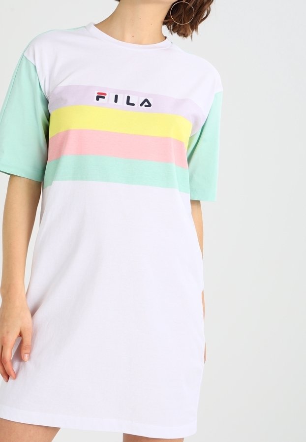 Biała sukienka z krótkim rękawem, ozdobiona pastelowymi poziomymi paskami w kolorze lawendy, żółtym, różowym i miętowym; na środku klatki piersiowej znajduje się logo FILA.