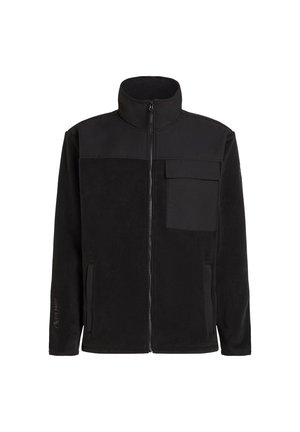Svart fleecejakke med høy krage, glidelås foran og brystlomme. Har glatt tekstur og kontrastpanel i stoff på den øvre delen.