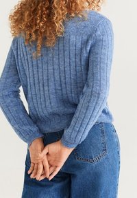 Jasnoniebieski sweter we wzór ściągacza, z długimi rękawami i okrągłym dekoltem, w zestawie z dżinsami z wysokim stanem.