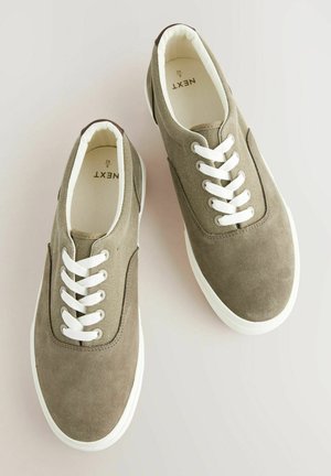 Pruun nubukist ja kangast tossud valgete paeltega, ümar varvas, kummist tallad ja pehme sisemine vooder. Brändi logo nähtav seest.