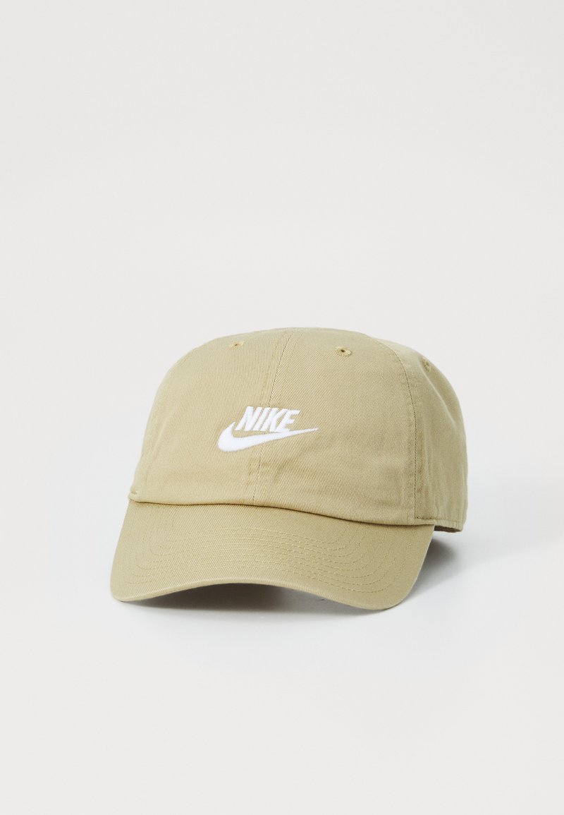 Boné de algodão bege com aba curvada, apresentando um logo branco da Nike bordado na parte da frente. Textura suave, design casual.