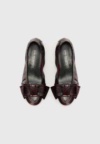 Ballerines en cuir bordeaux avec une finition texturée, ornées d'un grand nœud au niveau des orteils et d'une forme arrondie. Doublure intérieure douce et lisse.