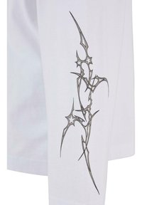 Hvit langermet skjorte med et metallisk sølv abstrakt design på venstre arm, som viser intrikate linjer og former.