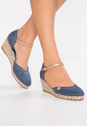 Denim wedge espadrilles med en vævet jute hæl, med en beige ankelrem og dekorativt knapdetalje på overdelen.
