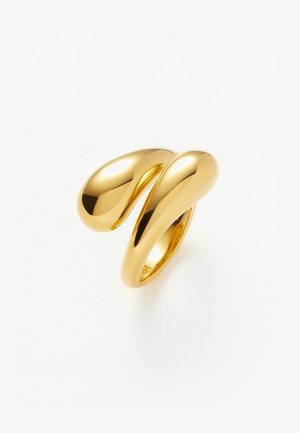 Anneau doré brillant au design moderne et abstrait, avec deux extrémités lisses et arrondies qui se courbent et s'entrelacent.