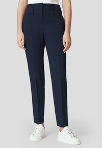 Granatowe spodnie o kroju spodni eleganckich z wysokim stanem, przeszyciami z przodu i gładką teksturą, zestawione z białymi trampkami. Prosty i nowoczesny design.