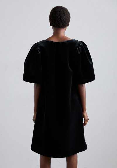 Black velvet dress with a loose fit, short puff sleeves, and a rounded neckline. The fabric has a smooth, soft texture.