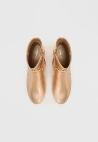 Botines en tono rosa dorado con un acabado metálico suave, puntera redonda, cremallera lateral y un diseño minimalista. Interior suave y forrado visible.