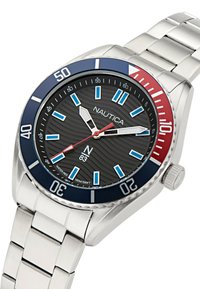 Montre Nautica avec un bracelet en acier inoxydable, un cadran texturé noir, une lunette bleu et rouge, des index des heures lumineux et un indicateur de date.