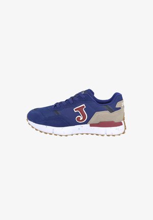 Zapato deportivo azul con una parte superior de ante, que presenta un destacado logo "J" en rojo, acentos beige y una suela blanca con motas.