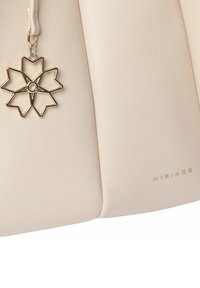 Beige skuldertaske lavet af glat syntetisk materiale, der har en fremtrædende charm formet som en stjerne i guld og sølv samt et præget logo.