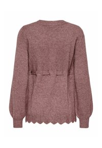 Adīta džemperis putekļu rozā krāsā ar viļņotu apakšmalu, saspringtu vidukli ar lentu akcentiem un gariem, pūkainiem piedurknēm, lai pievienotu tekstūru.