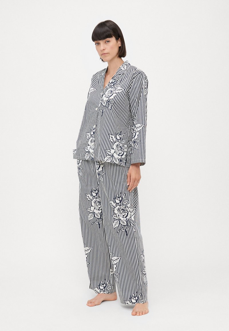 Striped pajama set in navy and white, featuring floral patterns. The top has a collar and long sleeves; pants are loose-fitting with matching design.