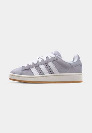 Gray suede sneakers with white stripes, round toe, and rubber sole. Features perforations on the side and textured heel tab.