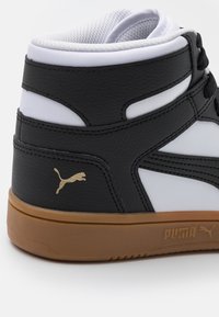 Czarno-białe sneakersy wysokie z teksturowanej skórzanej cholewki, z wyściółką w kołnierzu i gumową podeszwą. Zawierają złote logo Pumy.