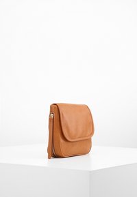Tan lædertaske med flaplukning og sidelukning med lynlås. Glat overflade, rektangulær form, minimalistisk design. Ingen synlige mønstre eller accenter.