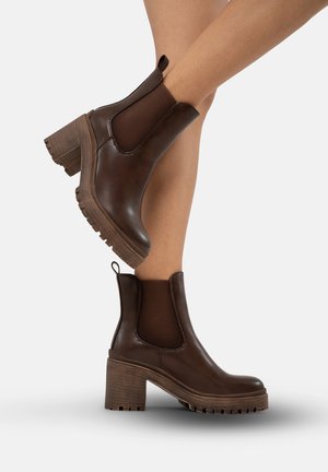 Braune Leder-Stiefeletten mit elastischen Seiteneinsätzen, klobigem braunem Absatz und strukturiertem Gummisohle, mit einer Zuglasche an der Rückseite.