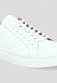 Białe skórzane sneakersy z okrągłym noskiem, płaskimi białymi sznurowadłami i jasnobrązowymi akcentami na języku. Gładka tekstura z widocznymi detalami przeszycia.