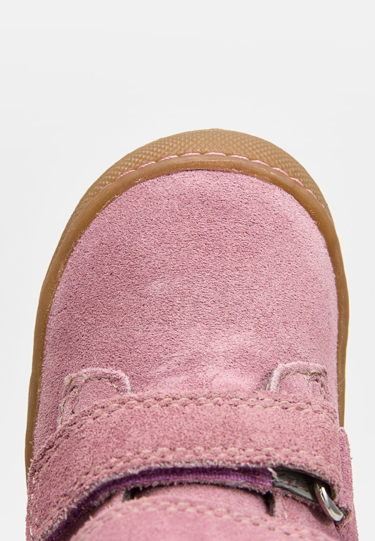 Rosa Wildlederschuh für Kinder mit abgerundetem Zehenbereich, zwei Klettverschlüssen und einer Gummisohle. Mit Nahtverzierungen entlang der Kanten.