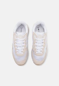 Białe sneakersy z beżowymi zamszowymi akcentami, z siateczkową cholewką, okrągłym noskiem, sznurowanym zapięciem i gumową podeszwą. Oznaczone napisem "Lacoste".